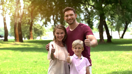Smiling family showing thumbs up, happy secure life, togetherness and relax