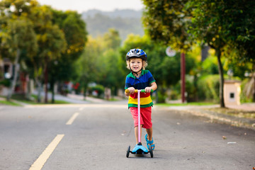 Child on scooter in summer. Kids skate.