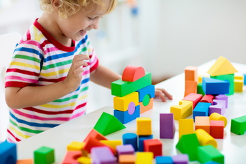 Kids toys. Child building tower of toy blocks.