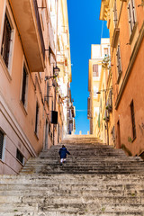 A detail of Frascati, in the Roman Castles. A little girl goes up a long staircase. Glimpse of blue sky between the buildings. Frascati, Rome, Lazio, Italy, Castelli Romani