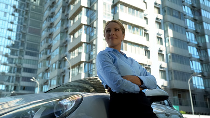 Confident lady in business suit standing leaning on new car, success and wealth