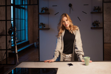 Young beautiful woman in the kitchen with smartphone. Looking for online cooking recipe.