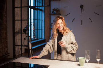 Young beautiful woman in the kitchen with smartphone. Looking for online cooking recipe.