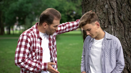 Dad scolding his son for bad behavior, education process, fathers and children