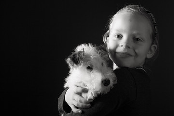 Cute young girl and her wire fox terrier puppy in the studio in monochrome
