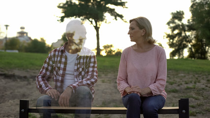 Depressed old woman sitting on bench, husband appearing beside, loss, memories