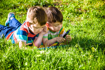 Beautiful happy children, boy brothers, exploring nature with magnifying glass, summertime