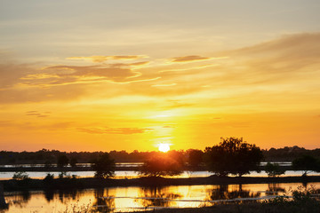 Sunset in the lake. beautiful sunset behind the clouds above the over lake landscape background. dramatic sky with cloud at sunset