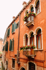 Street view with windows and balconies with flowers and old houses in Venice, Italy.