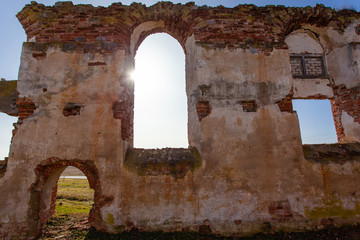 Obraz premium ruined wall with arched windows and an entrance in the ruins of an old medieval red brick building