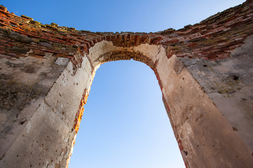 arch window against the blue sky in the ruins of an old medieval red brick building