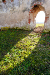 bright sunlight through an arched entrance to a wall on the ruins of an old medieval red brick building