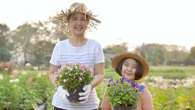 Slow motion Happy Asian mother and daughter planting flower together in the garden