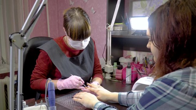 Manicurist pushing a customer's cuticle back
