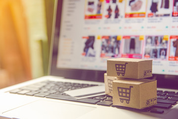 Obraz premium Shopping online concept - Shopping service on The online web. with payment by credit card and offers home delivery. parcel or Paper cartons with a shopping cart logo on a laptop keyboard