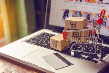Shopping online. Credit card and cardboard box or parcel with a shopping cart logo in a trolley on...