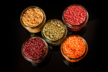 top view of small glass jars filled with different colors sea salt