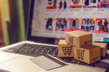 Shopping online concept - Shopping service on The online web. with payment by credit card and offers home delivery. parcel or Paper cartons with a shopping cart logo on a laptop keyboard
