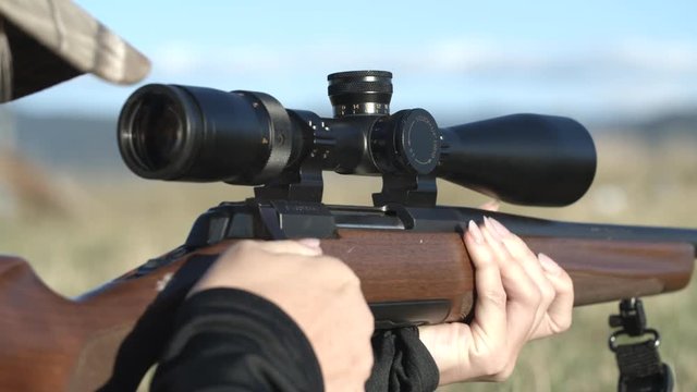 Closeup of female hands and rifle shell leaving gun at shooting range
