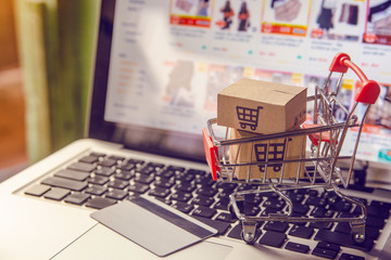 Shopping online concept - Parcel or Paper cartons with a shopping cart logo in a trolley on a laptop keyboard. Shopping service on The online web. with payment by credit card and offers home delivery.