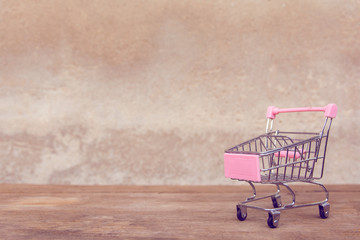 Shopping concept : Empty pink shopping cart on brown wood table. online shopping consumers can shop...