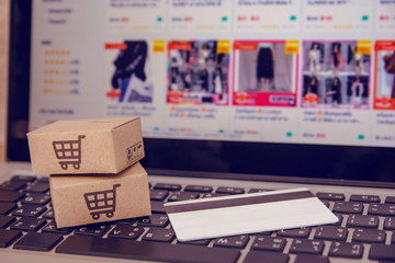 Shopping online concept - Shopping service on The online web. with payment by credit card and offers home delivery. parcel or Paper cartons with a shopping cart logo on a laptop keyboard