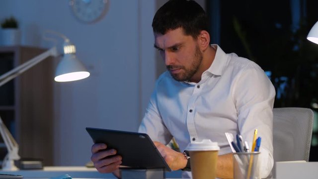 business, deadline and people concept - stressed businessman with tablet computer working at night office