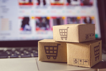 Online shopping : Paper cartons or parcel with a shopping cart logo on a laptop keyboard. Shopping...