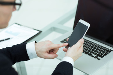 close up. a businessman uses a smartphone in the workplace