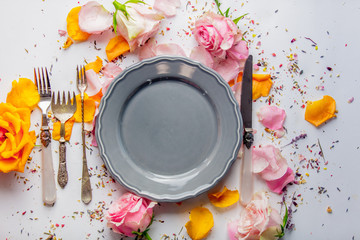 Plate, fork and knife with roses on white background