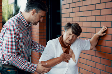 Son trying to help his mother who is having shortness of breath - obrazy, fototapety, plakaty