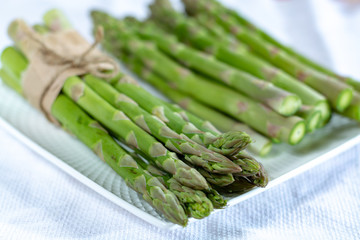 Fresh raw green asparagus vegetable on white board, close up