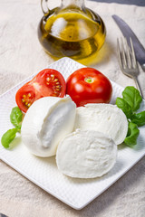Soft white Italian cheese Mozzarella buffalo served with fresh tomato, olive oil and green basil leaves
