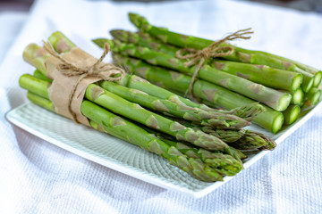 Fresh raw green asparagus vegetable on white board, close up