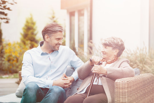 Senior Mother And Son Talking While Sitting On A Wicker Sofa Outdoor