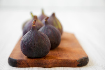 Fresh figs on rustic wooden board on a white wooden background, side view. Closeup. Selective focus.
