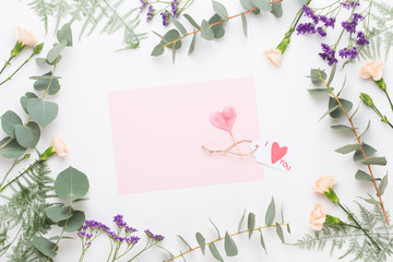 Flowers composition. Paper blank, carnation flowers, eucalyptus branches on pastel  background. Flat lay, top view, copy spaceFlat lay stiil life.