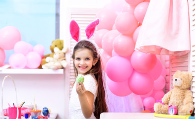 Obraz na płótnie Canvas little girl in Easter bunny ears holding colorful eggs