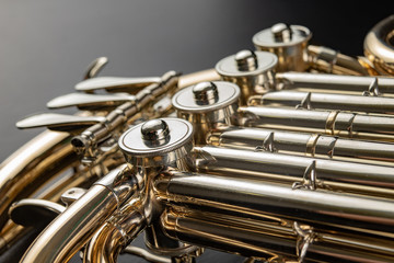 Naklejka premium French horn on a wooden table. Beautiful polished musical instrument.