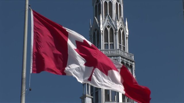 Close-up of Canadian Flag flapping in front of Parliament of Ottawa Canada