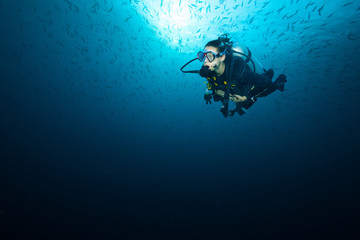 Fototapeta na wymiar Young woman scuba diver exploring coral reef