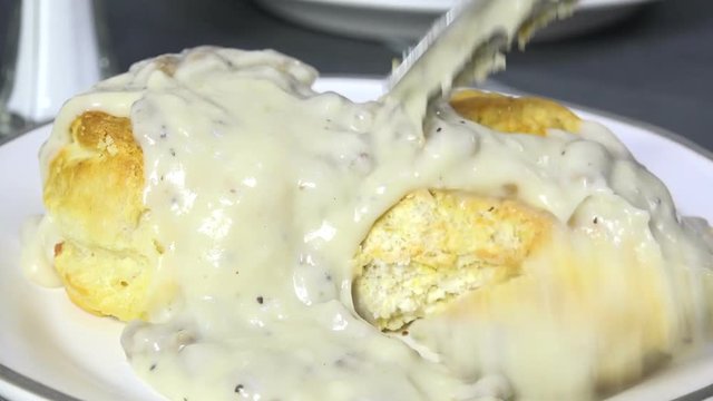 Closeup of eating biscuits and gravy, slow motion