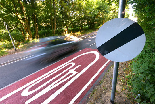 Speeding Car Going Past A National Speed Limit Sign.