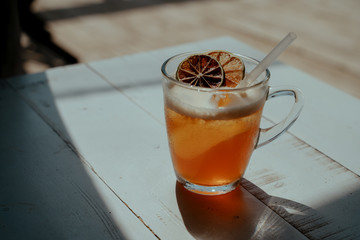 Cold ice tea with dried citrus fruits and cocktail straw tube in the glass