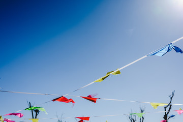 Colored flags against the sun waving in the wind at an outdoor party.