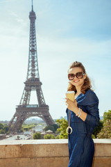 woman with coffee cup in front of Eiffel tower in Paris, France
