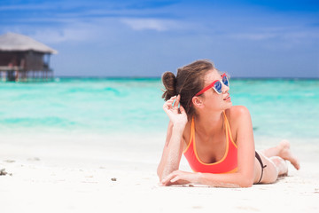 woman in bikini and straw hat lying on tropical beach