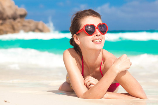 portrait of pretty woman in heart shaped sunglasses relaxing at tropical beach. La Digue, Seychelles