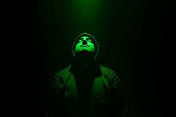 Man in a Dark Room Looking Up to a Green Light.