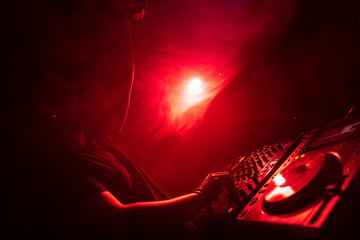 DJ Playing House and Techno Music in a Night Club. Mixing and Controlling the Music.